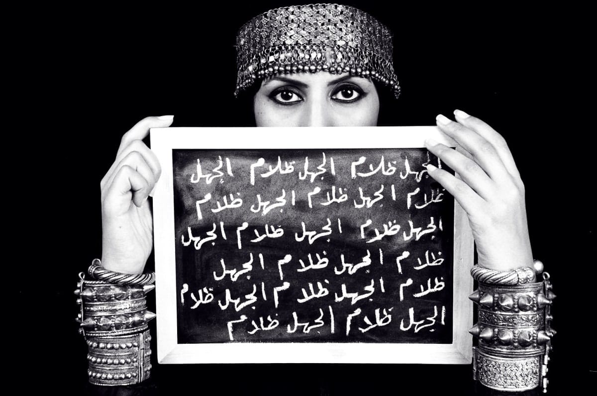 One poignant image features a university professor holding a chalkboard inscribed with the phrase “Ignorance is Darkness,”